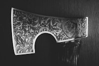 a black and white photo of an axe with a pattern on it