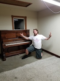 a man posing next to a piano in a room