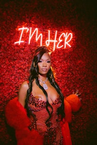 a woman in a red dress posing in front of a neon sign that says i'm her