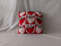 a crocheted strawberry pillow on a white surface