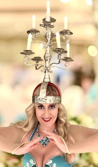 a woman in a blue dress with a candle holder on her head