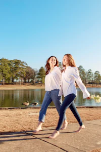 two women walking next to a lake
