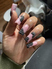 a person holding up a pink and black nail design