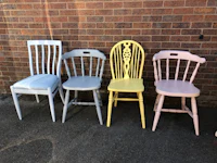 a row of painted chairs against a brick wall