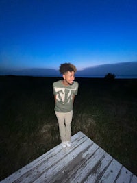a young man standing on a dock at night