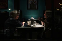 two people sitting at a table in a restaurant at night