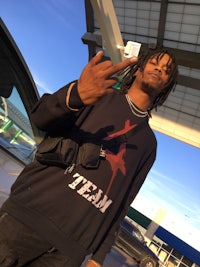 a man with dreadlocks standing next to a car