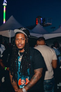 a man with dreadlocks standing in front of a carnival
