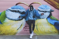 a man standing in front of a mural with birds on it