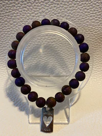 a bracelet with purple beads on a clear surface