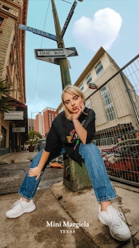 a woman is posing in front of a street sign