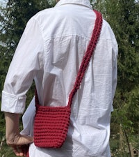 a woman wearing a red crocheted bag