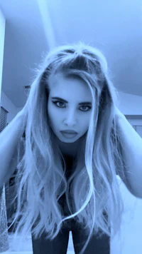 a girl with long blonde hair is posing in a mirror