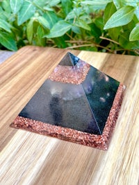 a black pyramid with red and black sand on top of a wooden table