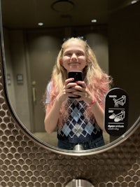 a girl taking a selfie in a bathroom mirror