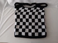 a black and white crocheted bag on a bed