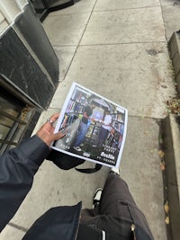 a person holding a newspaper on a sidewalk