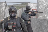 two men with guns in a paintball field