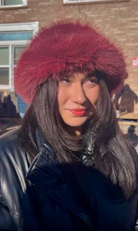 a woman wearing a burgundy fur hat
