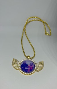 a gold necklace with a blue and purple angel wing pendant