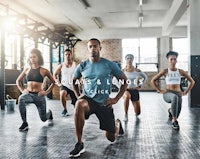 a group of people doing squats and lunges in a gym