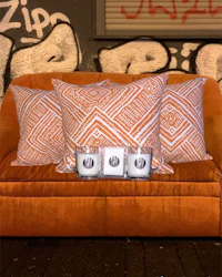 an orange couch with pillows and candles in front of a graffiti wall