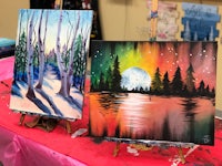 two paintings on easels with trees on them