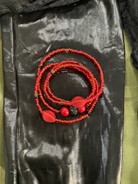 a red beaded bracelet on a black leather bag