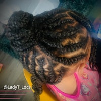 a little girl is sitting in a chair with her hair in a bun