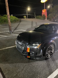 a black audi tt parked in a parking lot at night