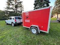 a red suv is parked next to a red trailer