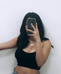 a woman in a black top and jeans taking a selfie