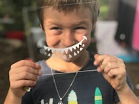 a young boy holding up a paper cut out of a shark