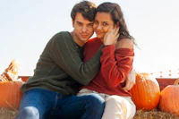 a young couple embracing in front of pumpkins