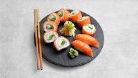japanese sushi on a black plate with chopsticks