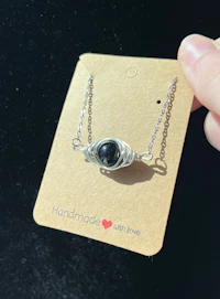 a person holding a necklace with a black stone on it