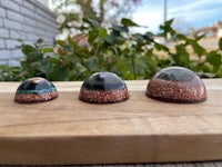 three glass domes sitting on top of a wooden cutting board