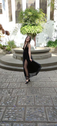 a woman in a black dress posing in front of a building