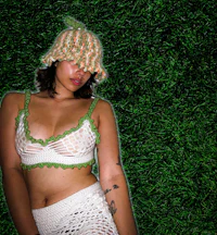 a woman wearing a crocheted hat posing on grass