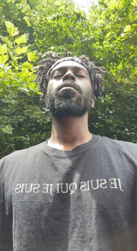 a man with dreadlocks wearing a black t - shirt