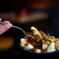 a person is holding a fork while eating a bowl of food