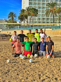 a group of men posing for a photo on the beach