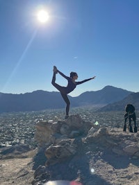 a woman doing yoga on top of a mountain