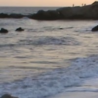 a woman walking on a beach at sunset