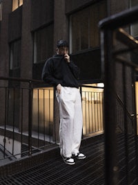 a man standing on a railing while talking on his cell phone