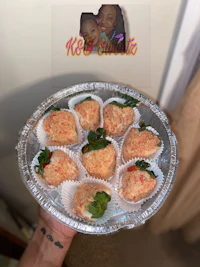 a person holding up a tray of stuffed strawberries