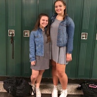 two girls standing in front of green lockers