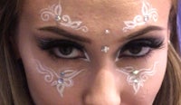 a woman with a white face painted with rhinestones