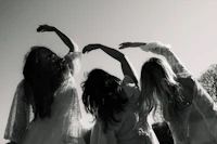 black and white photo of three women holding hands in the air