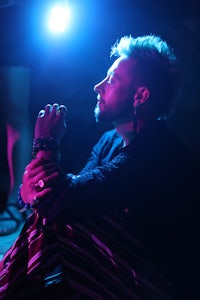 a man crouching down in front of a blue light